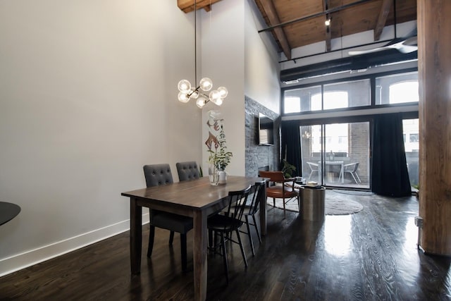 dining room with baseboards, a chandelier, beam ceiling, a towering ceiling, and wood finished floors