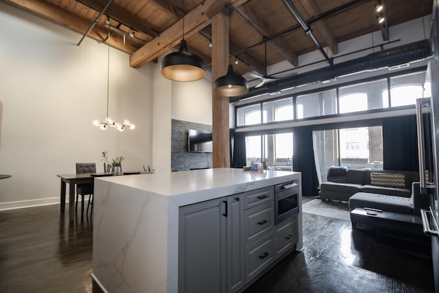 kitchen with stainless steel microwave, dark wood-type flooring, a high ceiling, and wooden ceiling