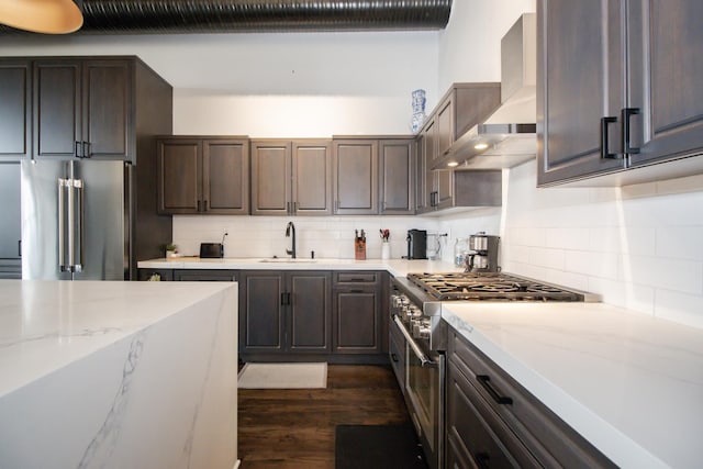 kitchen with dark wood-style flooring, a sink, dark brown cabinetry, wall chimney range hood, and high quality fridge