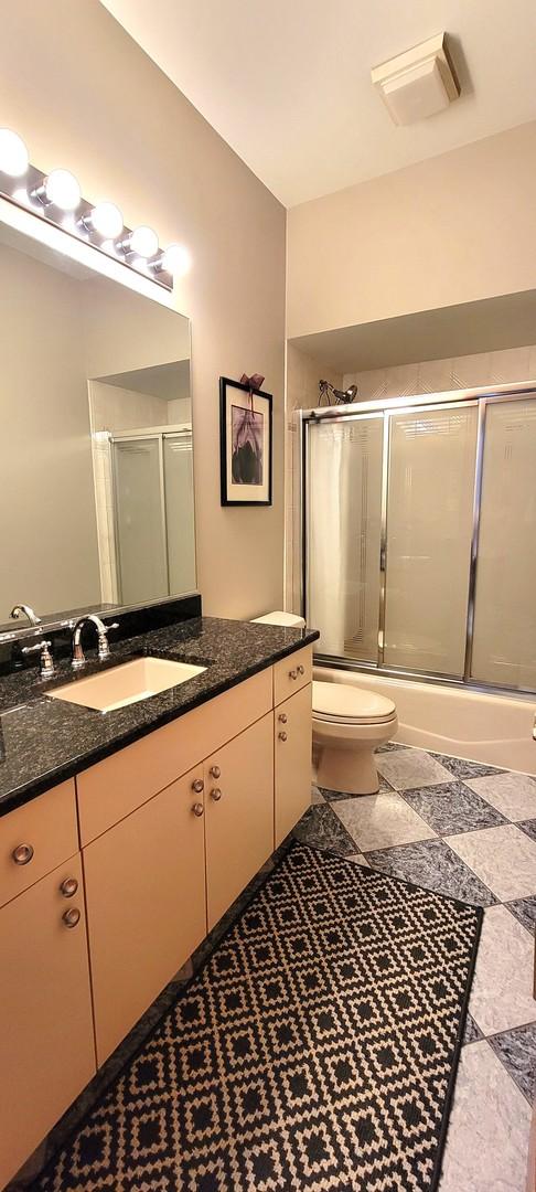 full bath with vanity, toilet, visible vents, and enclosed tub / shower combo