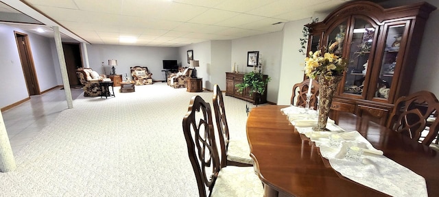 carpeted dining area with a drop ceiling and baseboards