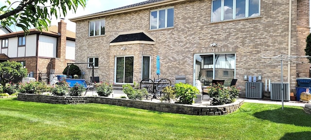 back of property featuring brick siding, central air condition unit, a lawn, and a patio