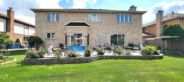 back of house featuring a patio area, a lawn, and brick siding