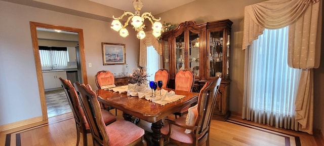 dining area with light wood-style floors and a notable chandelier