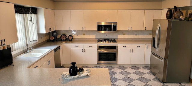 kitchen with light floors, a sink, decorative backsplash, light countertops, and stainless steel appliances