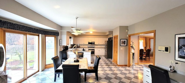 dining area featuring a ceiling fan, light floors, and baseboards