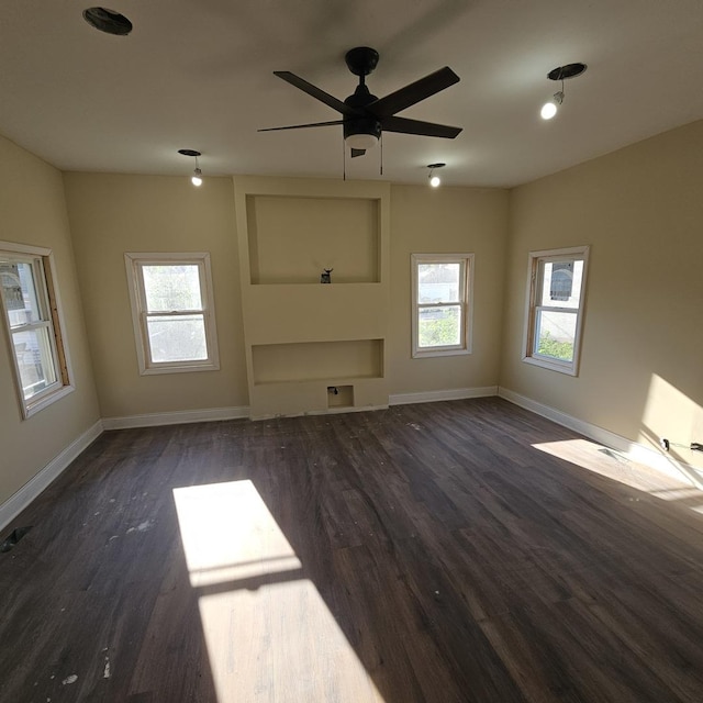 unfurnished living room featuring wood finished floors, a healthy amount of sunlight, and baseboards