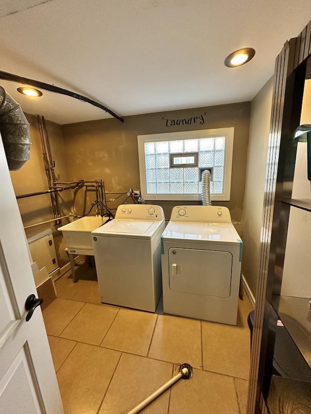 clothes washing area with a sink, tile patterned flooring, laundry area, and washing machine and clothes dryer