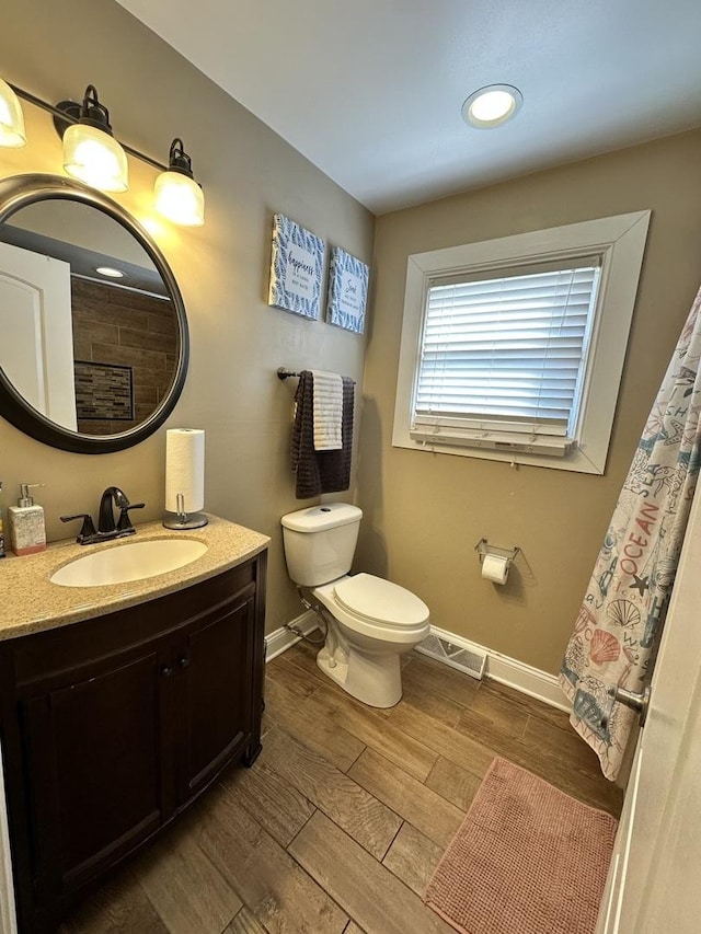 bathroom featuring baseboards, toilet, wood finished floors, and vanity