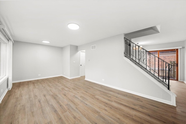 interior space featuring visible vents, baseboards, wood finished floors, and stairs