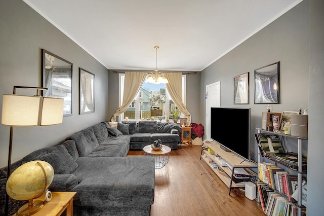 living area featuring a notable chandelier, ornamental molding, and wood finished floors