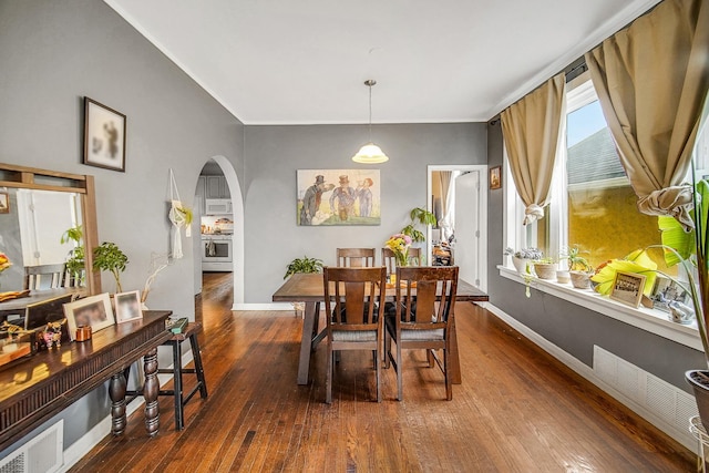 dining area featuring hardwood / wood-style flooring, baseboards, arched walkways, and visible vents