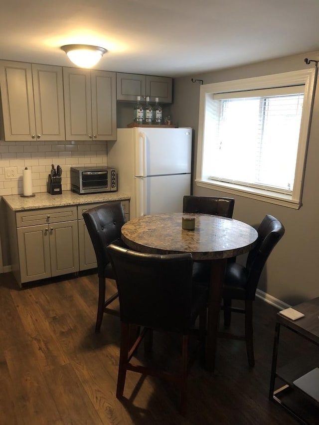 dining space featuring a toaster, baseboards, and dark wood-style flooring