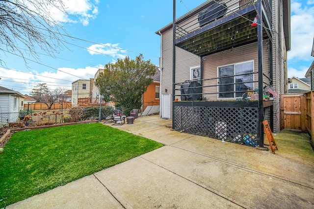 rear view of house with a fenced backyard, a lawn, and a patio