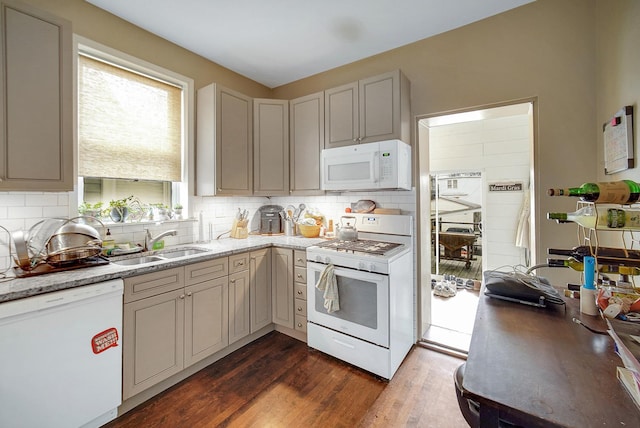 kitchen with tasteful backsplash, a sink, light stone countertops, white appliances, and dark wood-style flooring