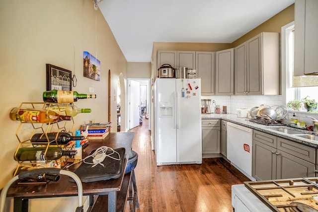 kitchen featuring dark wood-type flooring, gray cabinetry, a sink, tasteful backsplash, and white appliances