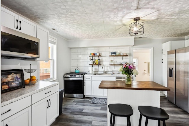 611 Mccarthy Rd, Lemont, IL 60439 - kitchen featuring stainless steel appliances, a sink, wood counters, white cabinetry, and a kitchen bar