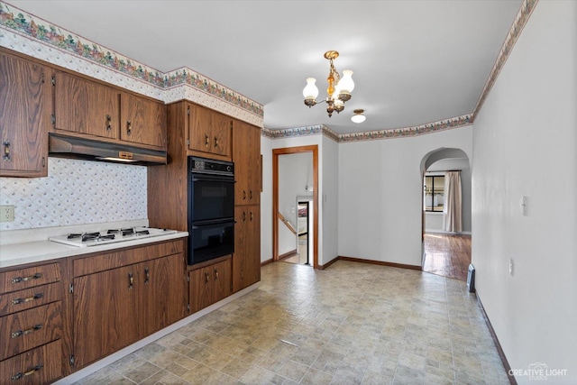 kitchen with dobule oven black, under cabinet range hood, backsplash, baseboards, and white gas stovetop