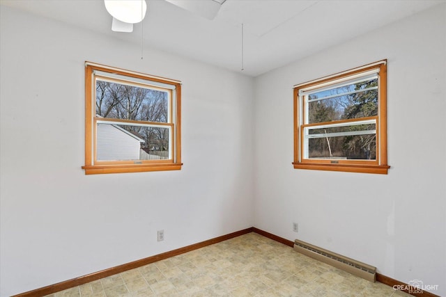 spare room with a baseboard radiator, baseboards, and light floors