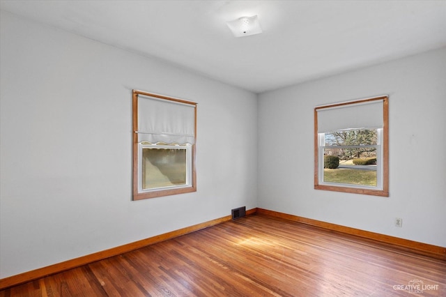 spare room with visible vents, baseboards, and wood finished floors