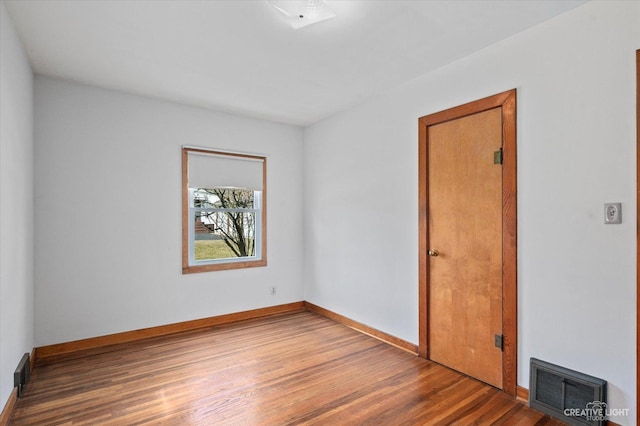 spare room with visible vents, baseboards, and wood finished floors