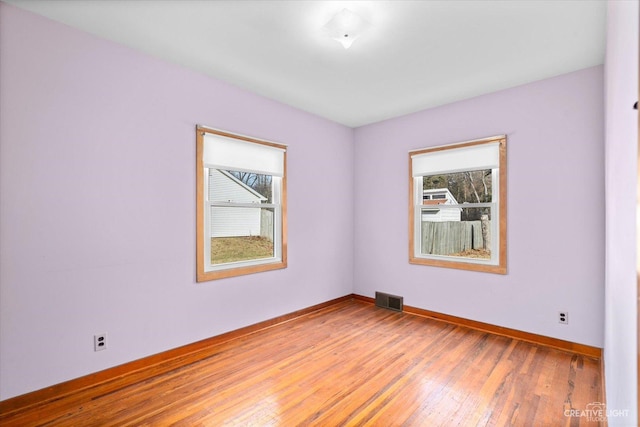 spare room featuring visible vents, light wood-style flooring, and baseboards