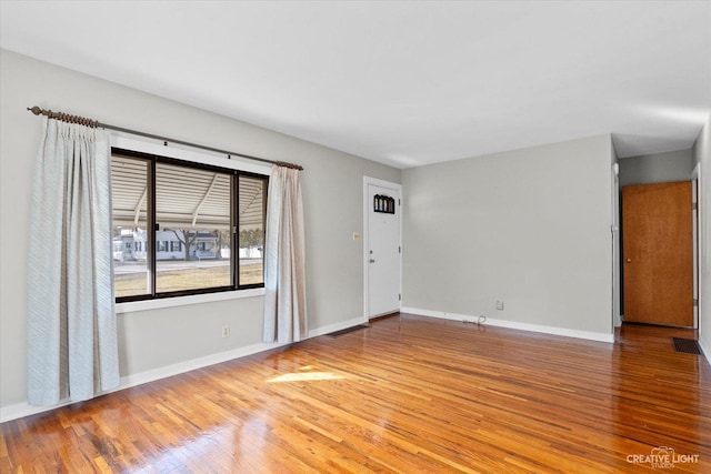 unfurnished living room featuring visible vents, baseboards, and wood finished floors