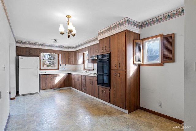 kitchen with backsplash, baseboards, a chandelier, light countertops, and freestanding refrigerator