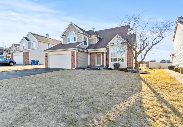 view of front of house featuring a front yard, fence, a garage, aphalt driveway, and brick siding