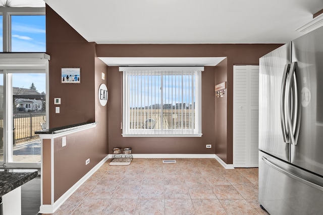 kitchen featuring a healthy amount of sunlight, baseboards, and freestanding refrigerator