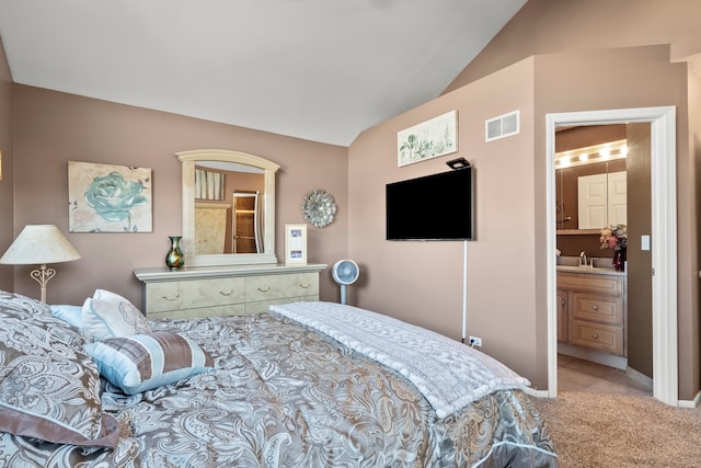 carpeted bedroom with vaulted ceiling, visible vents, ensuite bathroom, and a sink