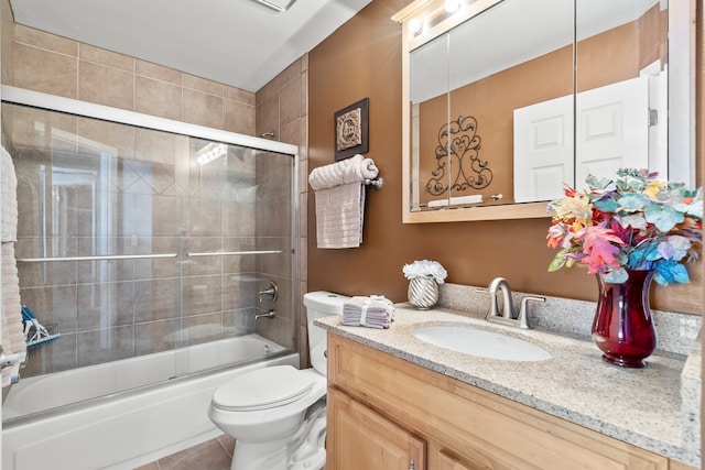 bathroom featuring tile patterned floors, vanity, toilet, and bath / shower combo with glass door