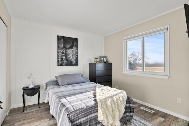 bedroom with wood finished floors, visible vents, and baseboards