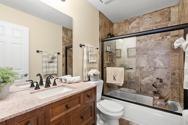 full bath with vanity, toilet, and shower / bath combination with glass door