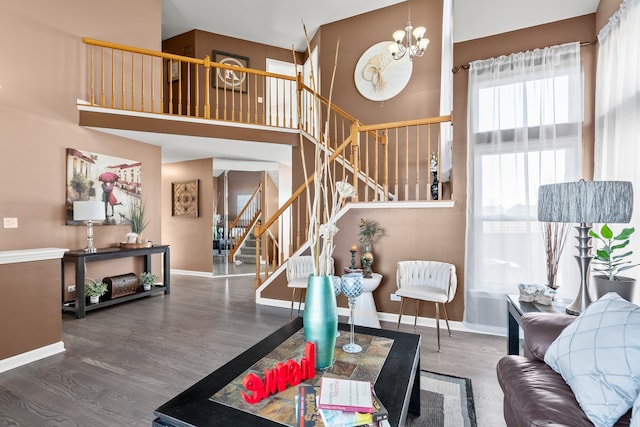 living area featuring wood finished floors, baseboards, stairs, a towering ceiling, and a chandelier