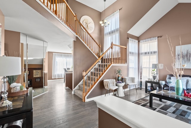 interior space featuring a towering ceiling, an inviting chandelier, wood finished floors, and stairs