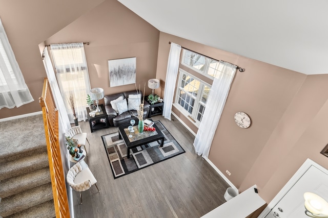 living area with stairway, lofted ceiling, baseboards, and wood finished floors