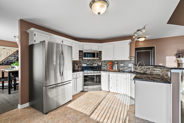 kitchen with tasteful backsplash, appliances with stainless steel finishes, a peninsula, white cabinetry, and a sink