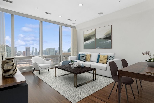 living room featuring a wall of windows, visible vents, a city view, and wood finished floors