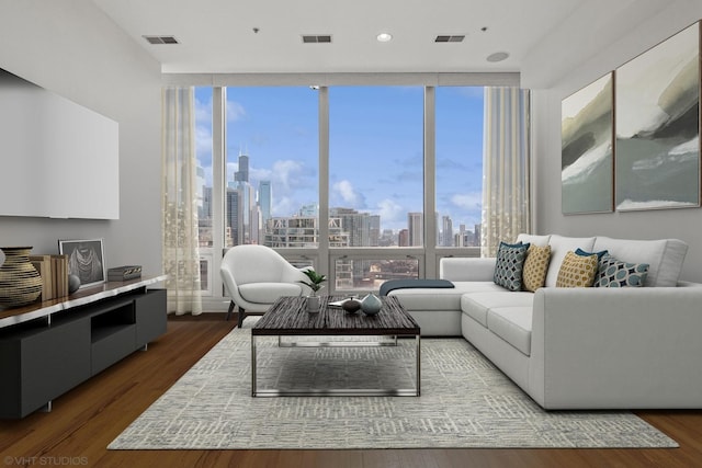 living area featuring visible vents, floor to ceiling windows, a view of city, and wood finished floors