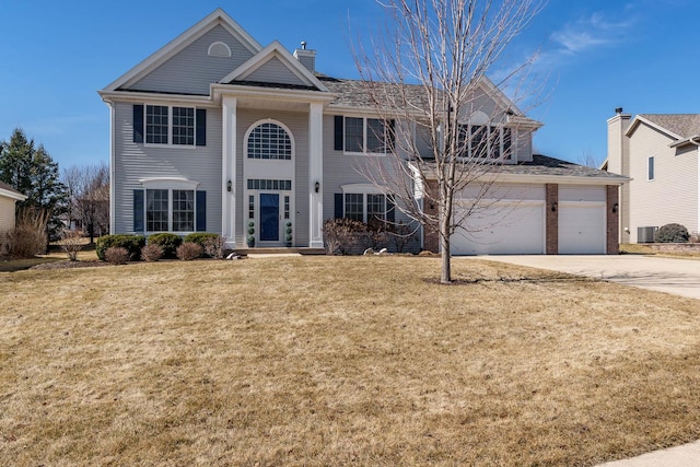 view of front of home with a garage, a front yard, a chimney, and driveway