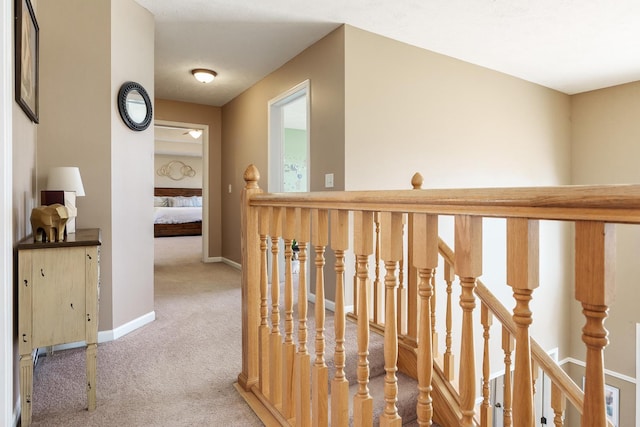 corridor with an upstairs landing, baseboards, and carpet floors