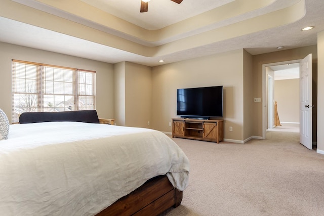 bedroom with a raised ceiling, a ceiling fan, baseboards, and light carpet