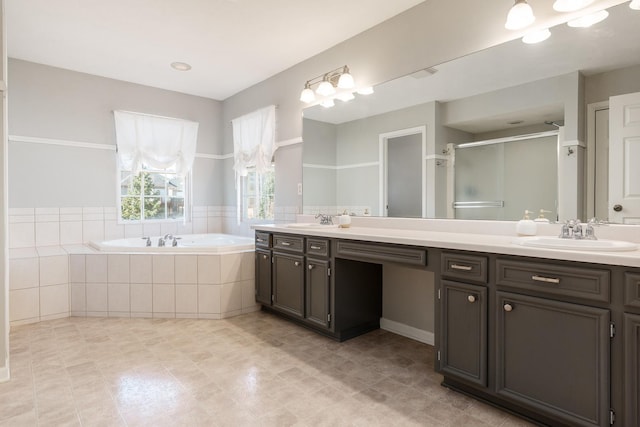 bathroom featuring double vanity, a stall shower, a garden tub, and a sink