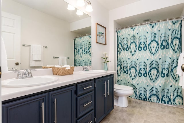 full bath featuring double vanity, curtained shower, toilet, and a sink