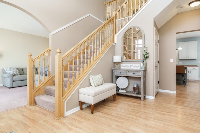 stairway featuring baseboards, arched walkways, and wood finished floors