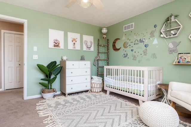 bedroom featuring visible vents, a crib, baseboards, carpet, and a ceiling fan