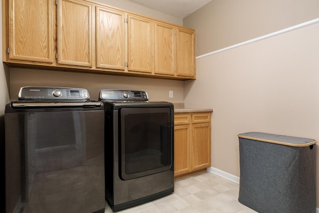 washroom with cabinet space, washing machine and dryer, baseboards, and light floors