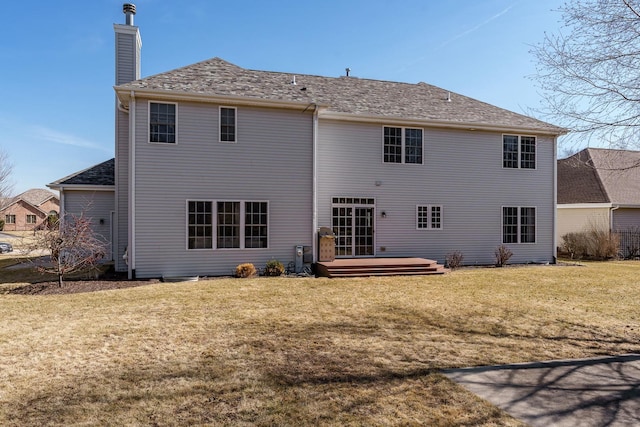 rear view of property with a yard, a deck, and a chimney