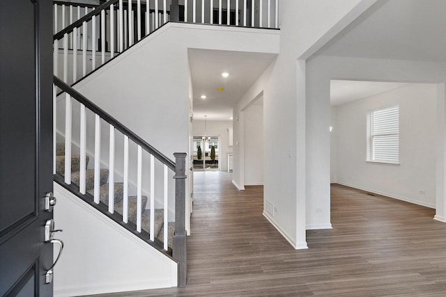 entryway featuring a high ceiling, stairway, wood finished floors, and baseboards